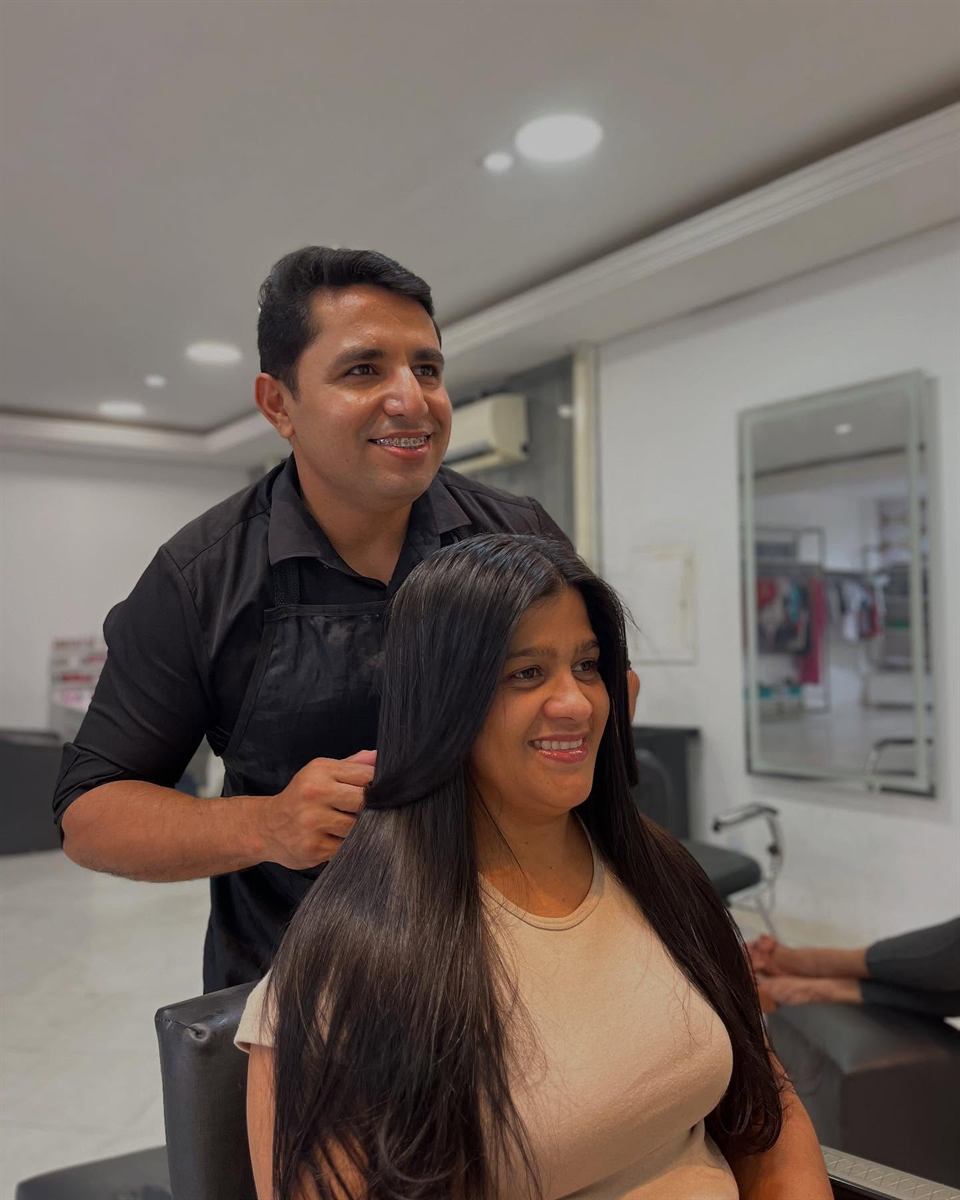 Roberto ao lado de uma cliente, conferindo o cabelo liso depois do atendimento